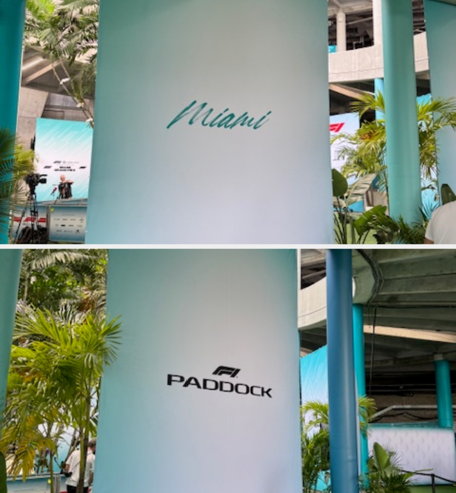 Two pillars with "Miami" and "F1 Paddock" text, surrounded by tropical plants and a modern architectural setting