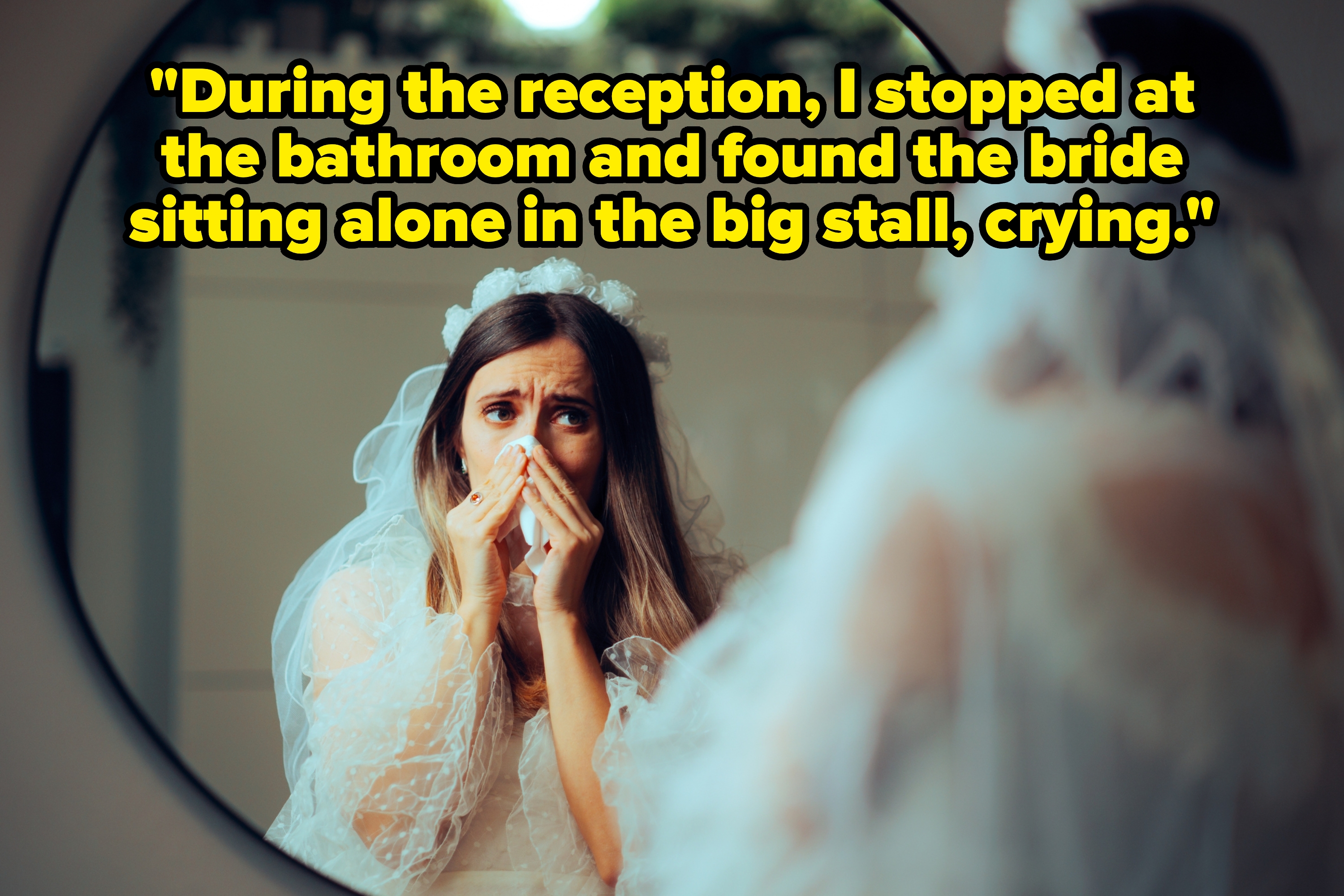 Bride in wedding dress looks anxious while gazing in the mirror, hands near face, veil and floral headpiece visible