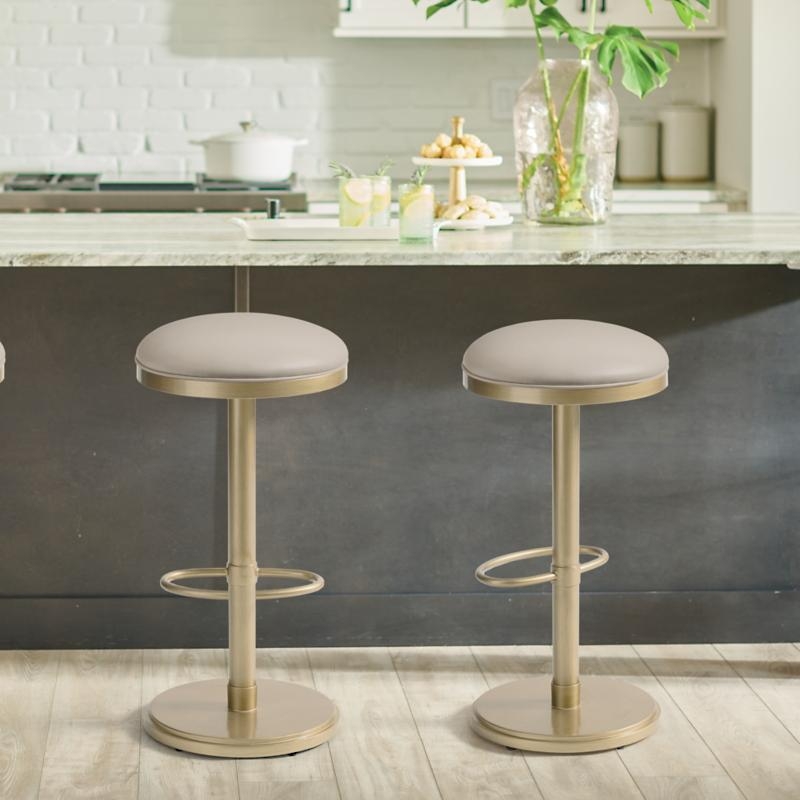 Two modern barstools with round seats and metal bases in a stylish kitchen setting, featuring a marble countertop and decorative items