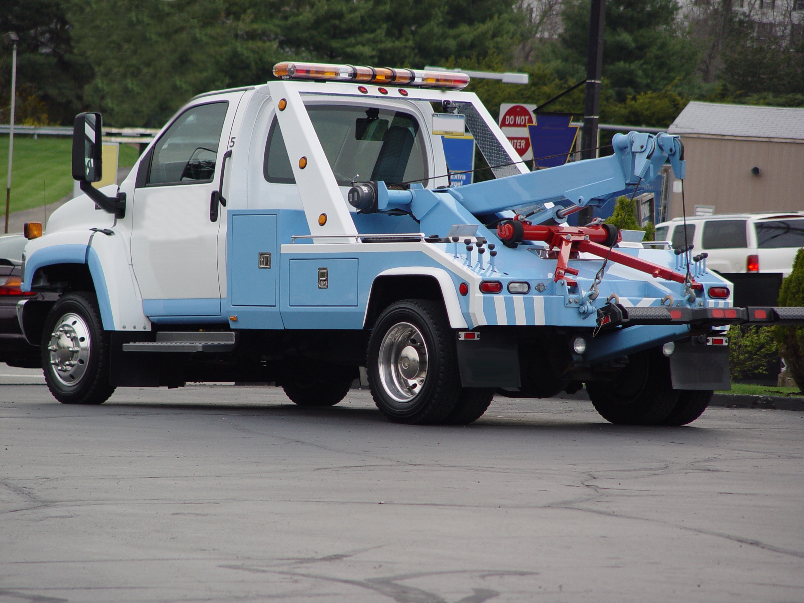 Tow truck parked in a lot with a hydraulic lift apparatus on the back, ready for towing vehicles