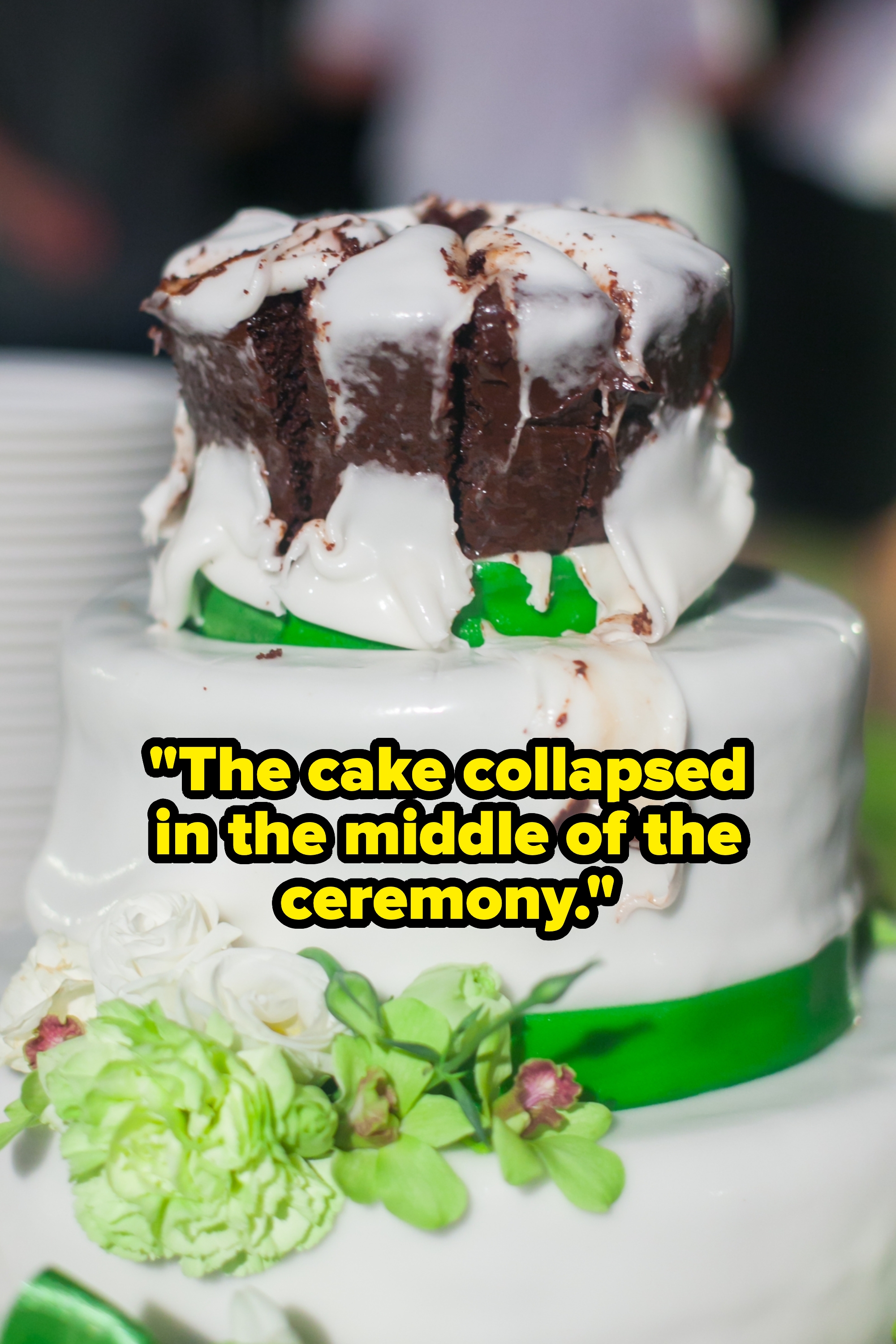 Wedding cake with white icing, topped with a smaller chocolate cake layer. Decorated with green ribbon and flowers