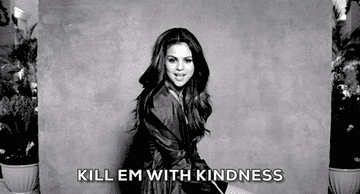 Person in stylish outfit smiling with "Kill Em With Kindness" text overlay