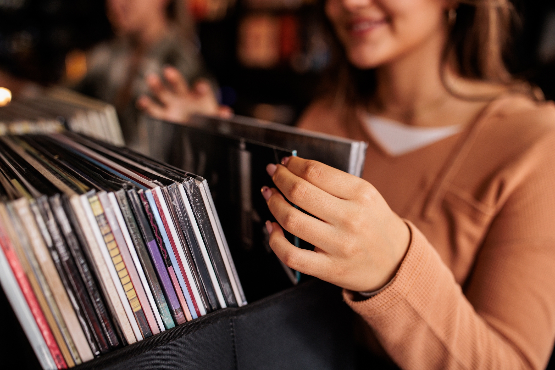 Person browsing vinyl records in a store, smiling and flipping through albums