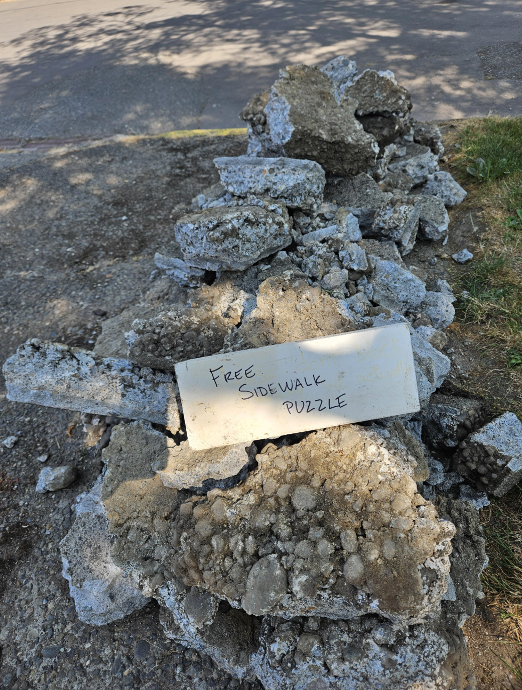 Pile of broken concrete pieces with a sign saying "Free Sidewalk Puzzle."