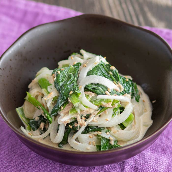 ボウルに盛られたほうれん草、玉ねぎ、ツナの和え物。上にごまが振りかけられている。