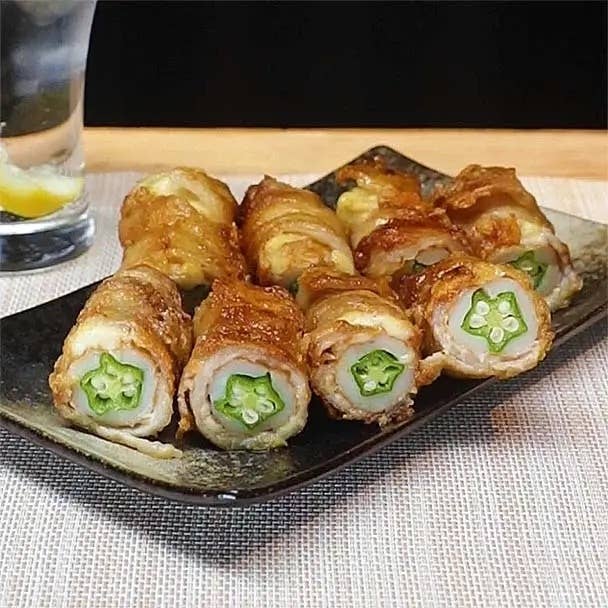 おくらを豚肉で巻いて揚げた料理が取り皿に盛られ、横にレモン入りのグラスがあります。