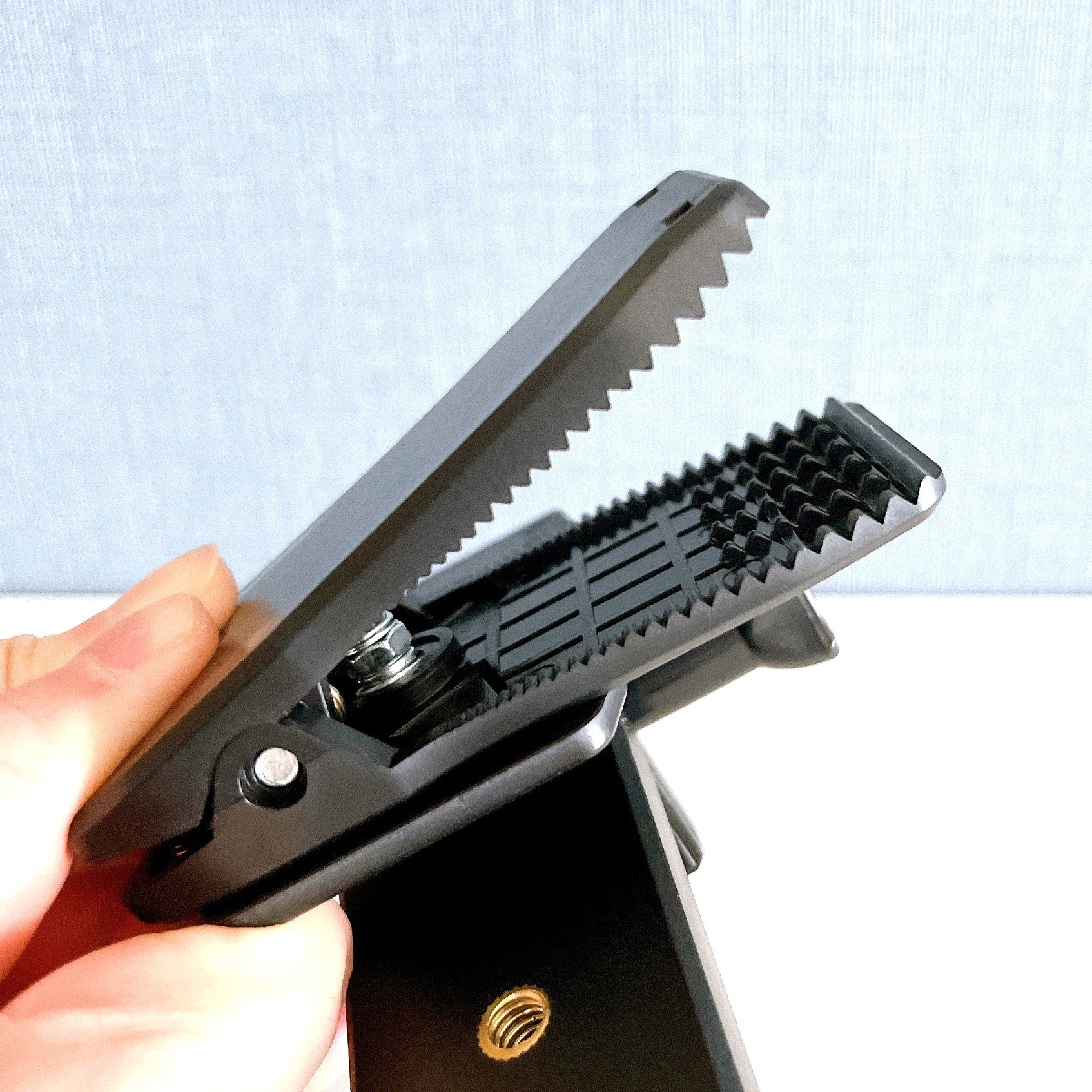 手で持たれたカメラやライトのマウントクリップ。バネ式で滑り止めの歯があります。