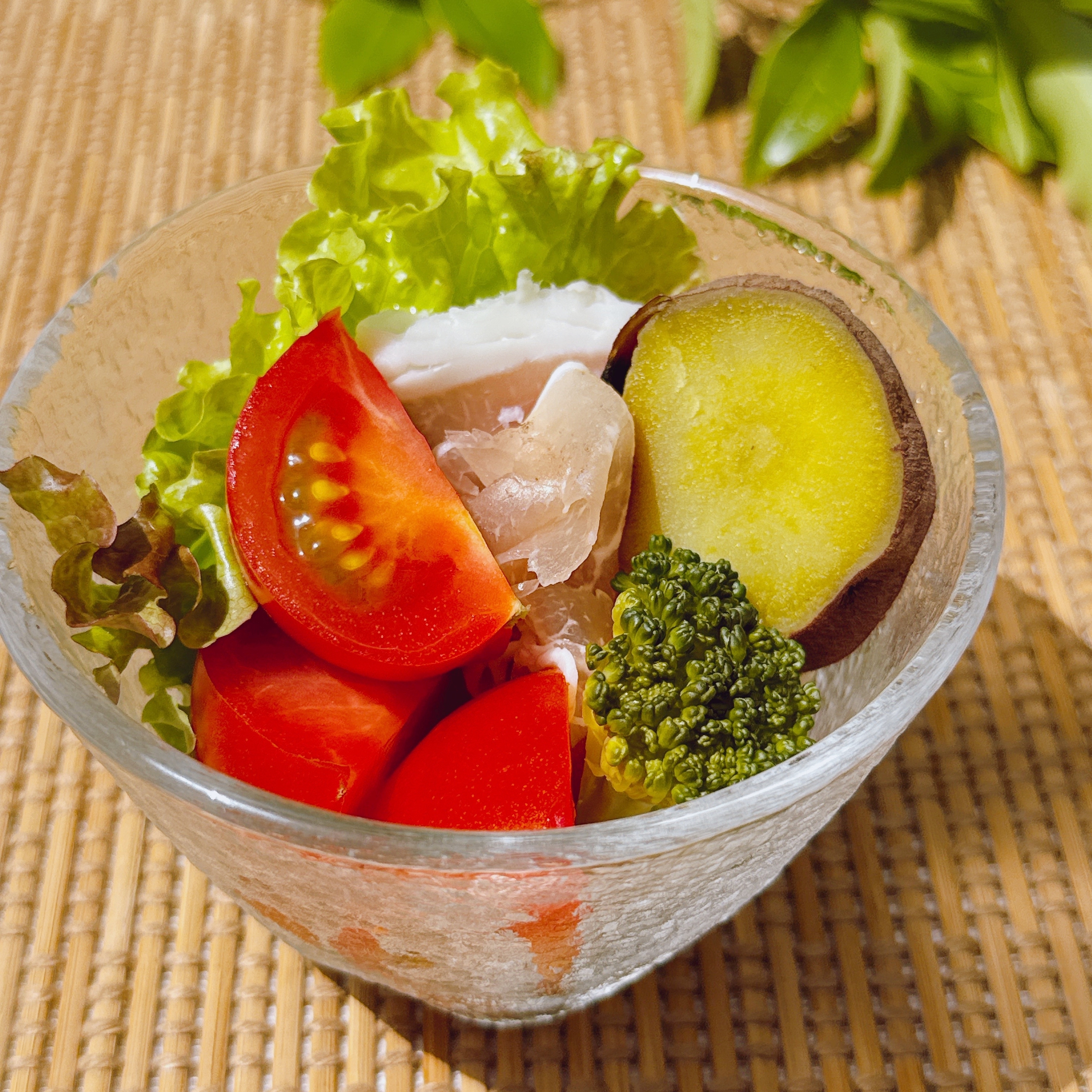 サラダボウルにレタス、トマト、ブロッコリー、さつまいも、鶏肉が入った新鮮な料理。