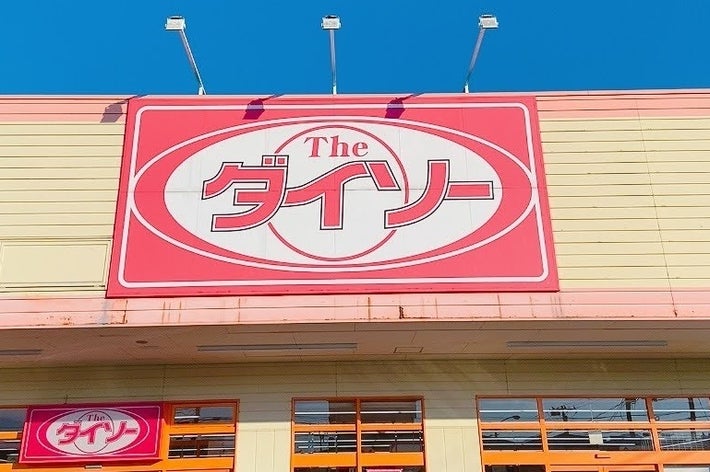 建物の正面にあるダイソーの看板。店の外に駐車された車も見える。