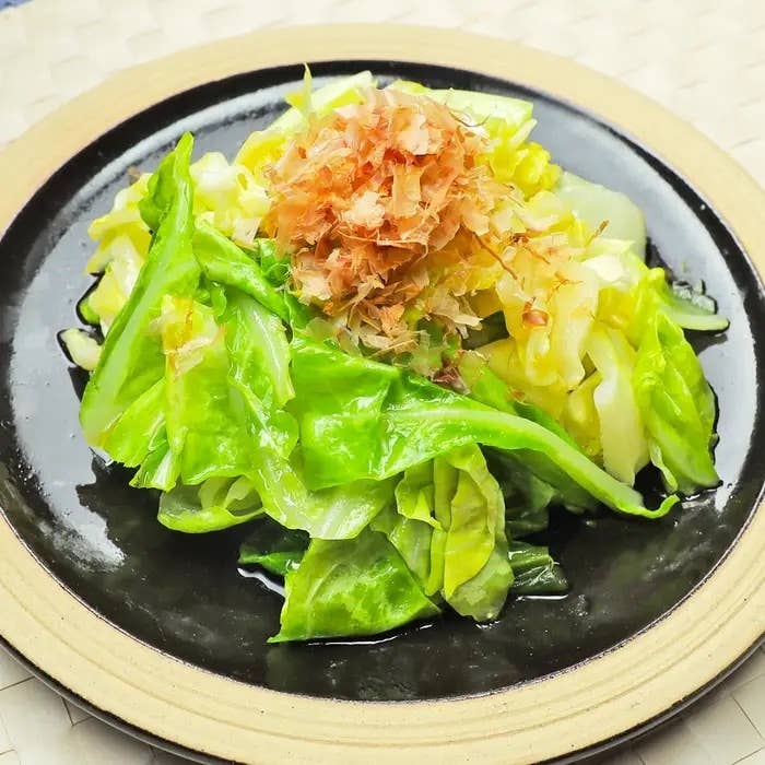 キャベツと鰹節の和風サラダが黒い皿にのっている。