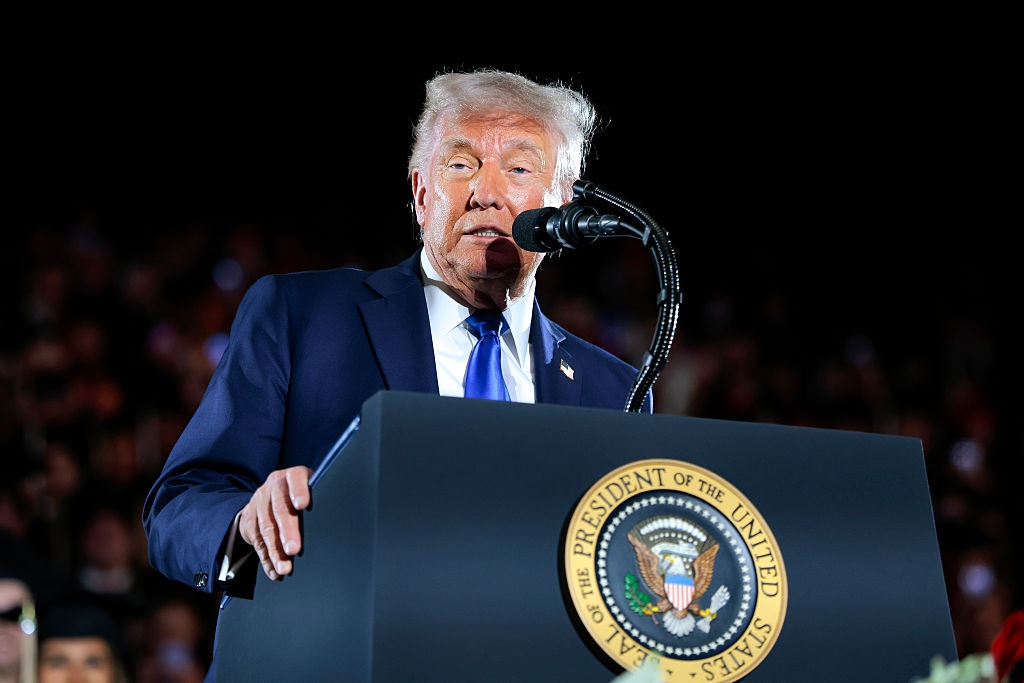 A person speaking at a podium with the presidential seal, addressing an audience
