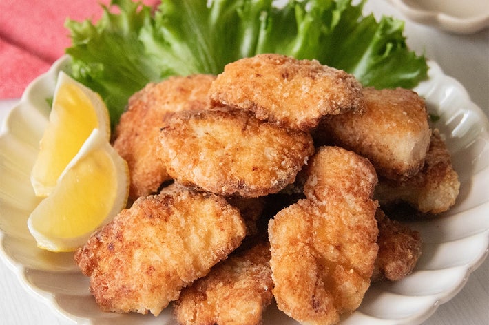 皿に盛られた鶏むね肉の塩こうじ唐揚げとレモンくし切り、背景にレタス。
