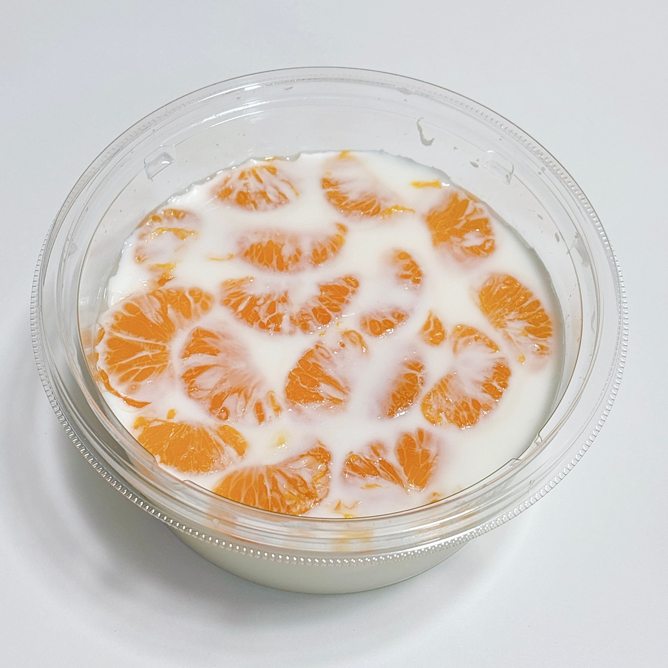 透明な容器に入ったマンダリンオレンジのスライスとヨーグルトのデザート。