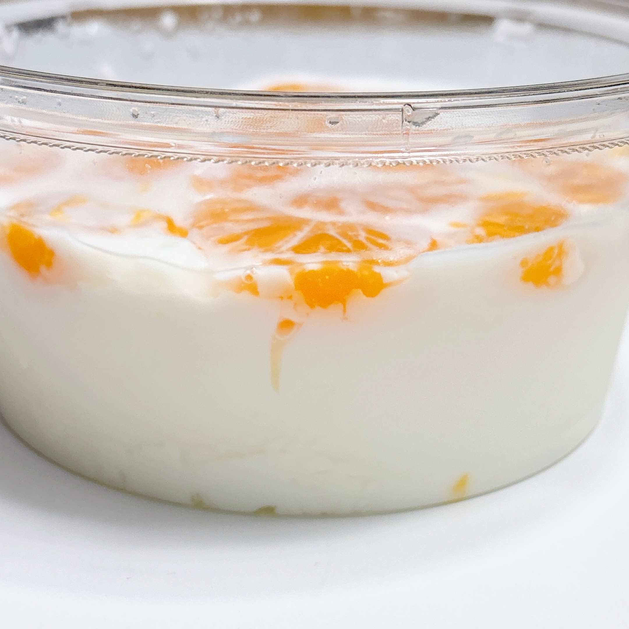 透明なガラスの容器に入ったオレンジがトッピングされたヨーグルト。