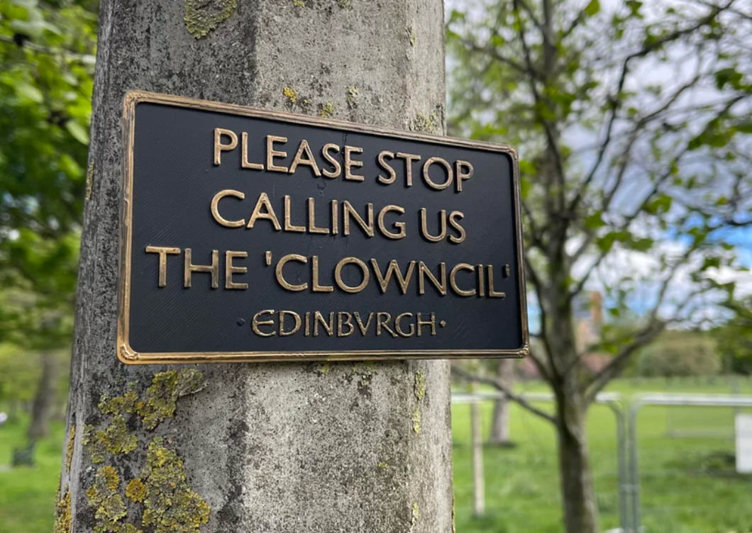 Plaque on a tree reads: "Please stop calling us the 'Clowncil' - Edinburgh."