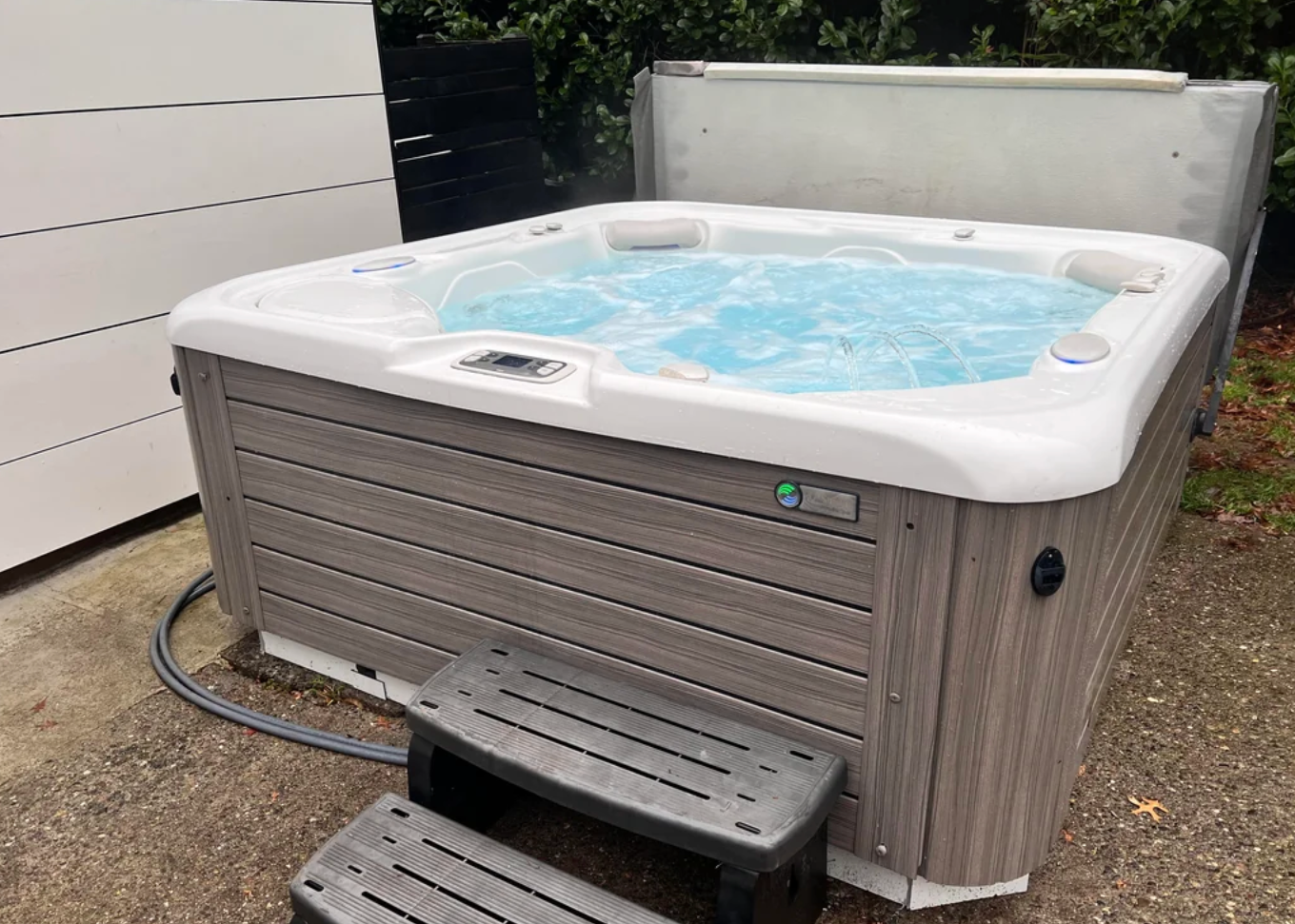 Hot tub on a patio with steps leading up, partially filled with bubbling water; text discusses regular use and effort in maintenance