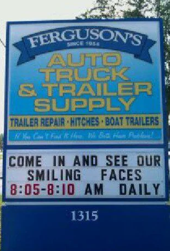 Sign for Ferguson's Auto Truck & Trailer Supply. It humorously invites people to see the staff's "smiling faces" from 8:05-8:10 AM daily