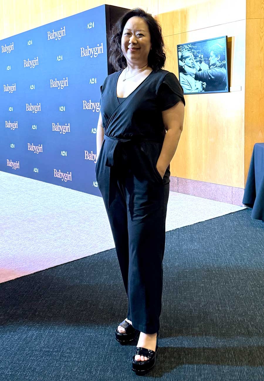 Person in a stylish black jumpsuit poses confidently at a media event