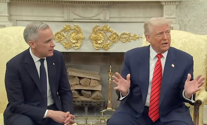 Two men sit in an ornate room with a fireplace; one gestures with open hands, both wear suits