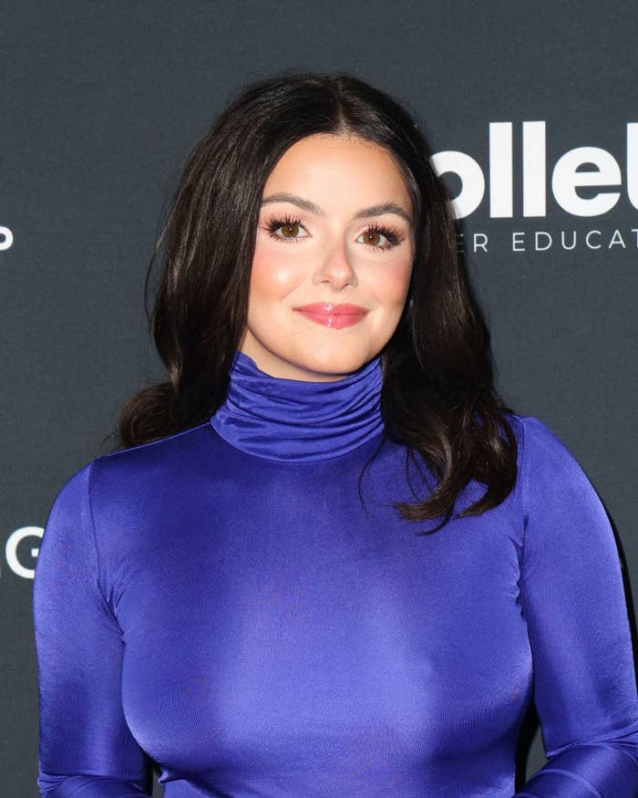 Person posing at an event wearing a long-sleeve, high-neck fitted dress
