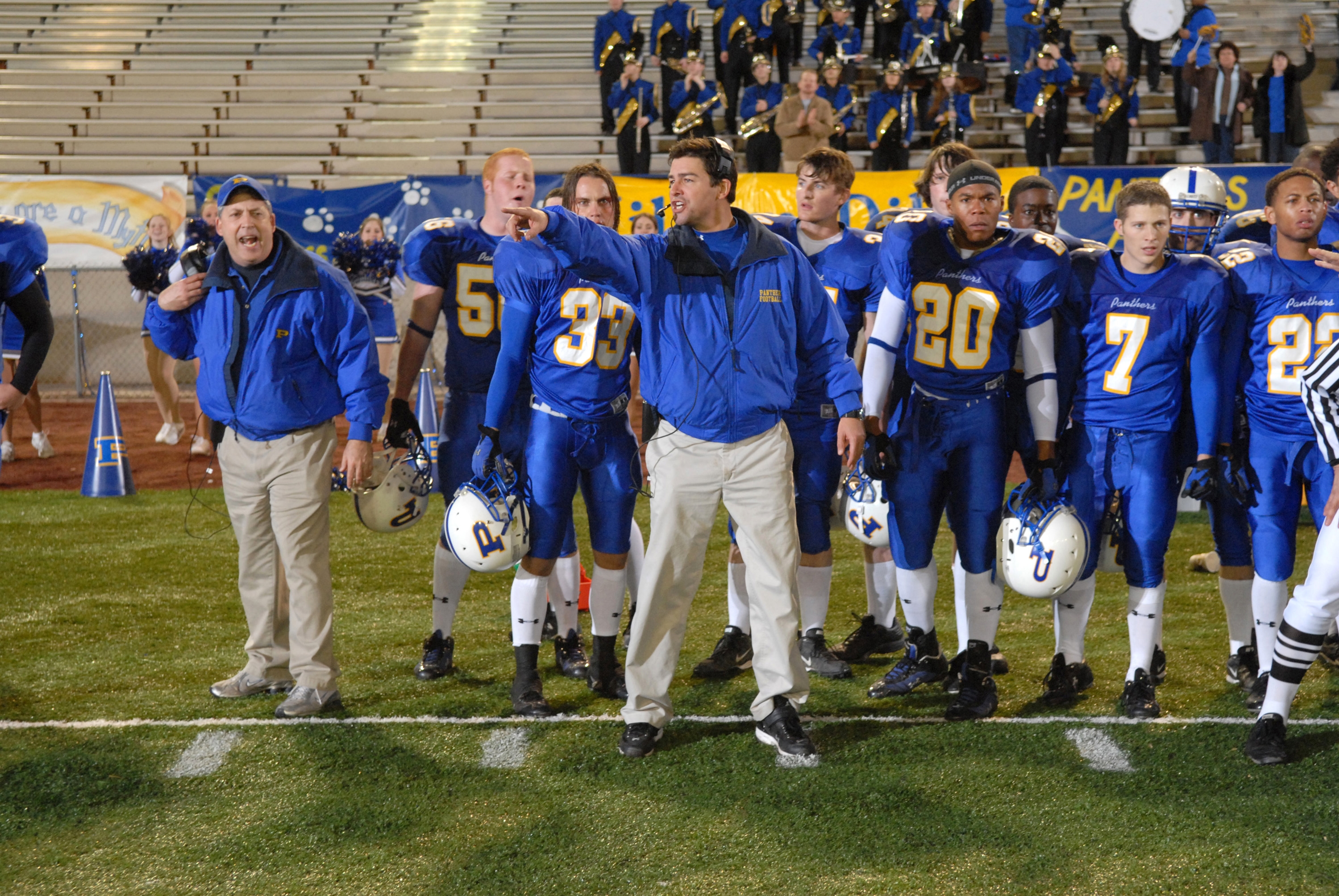 Football team in blue uniforms with a coach giving instructions on the sidelines during a game