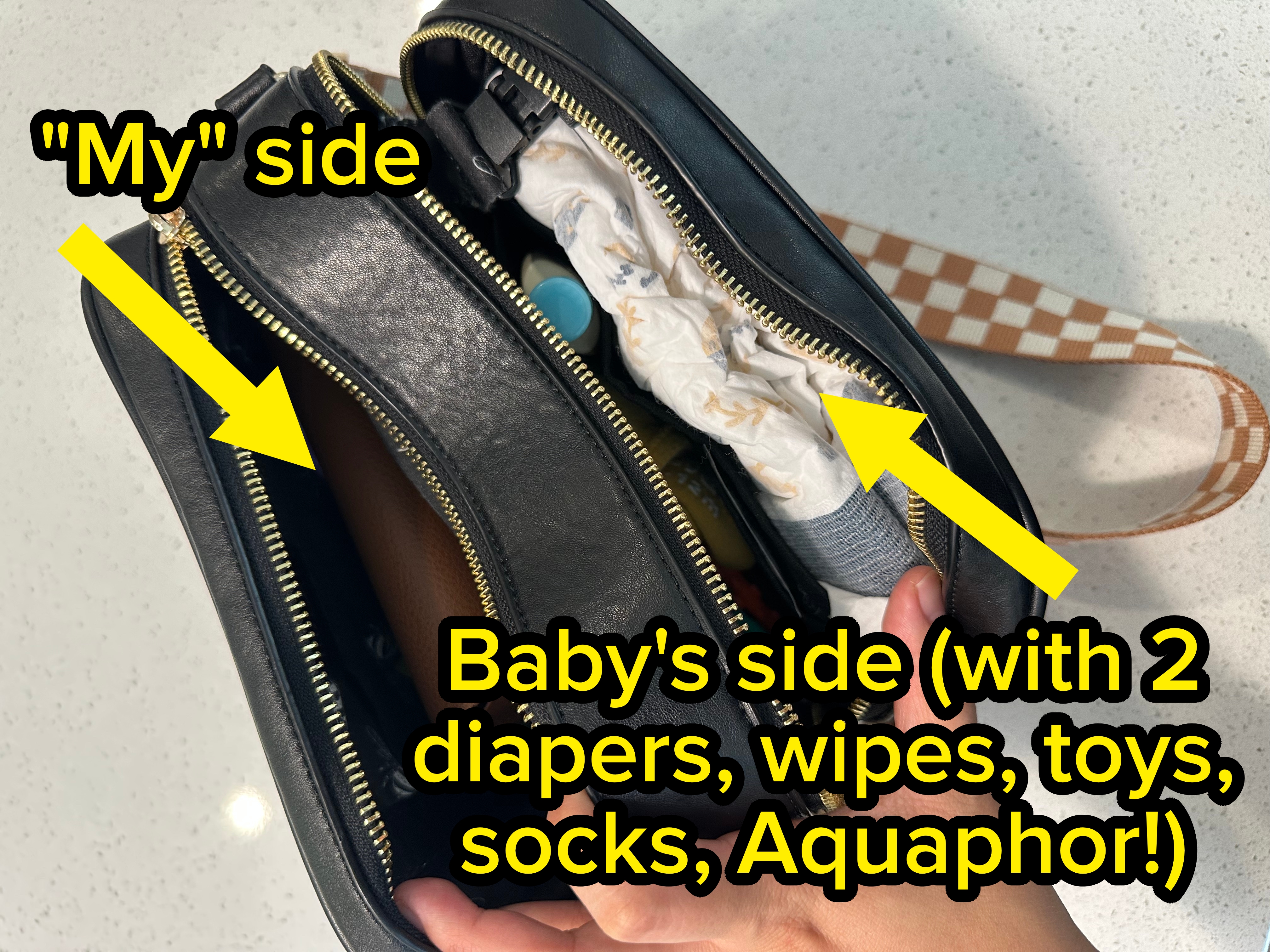 Open black handbag with visible items inside, including tissues, a bottle, and a wallet. A hand is holding the bag open against a light background