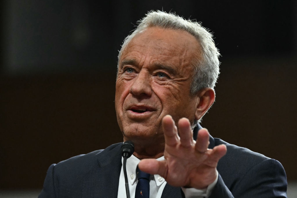 A person in a suit speaks passionately while gesturing with one hand, suggesting engagement in a formal event or discussion