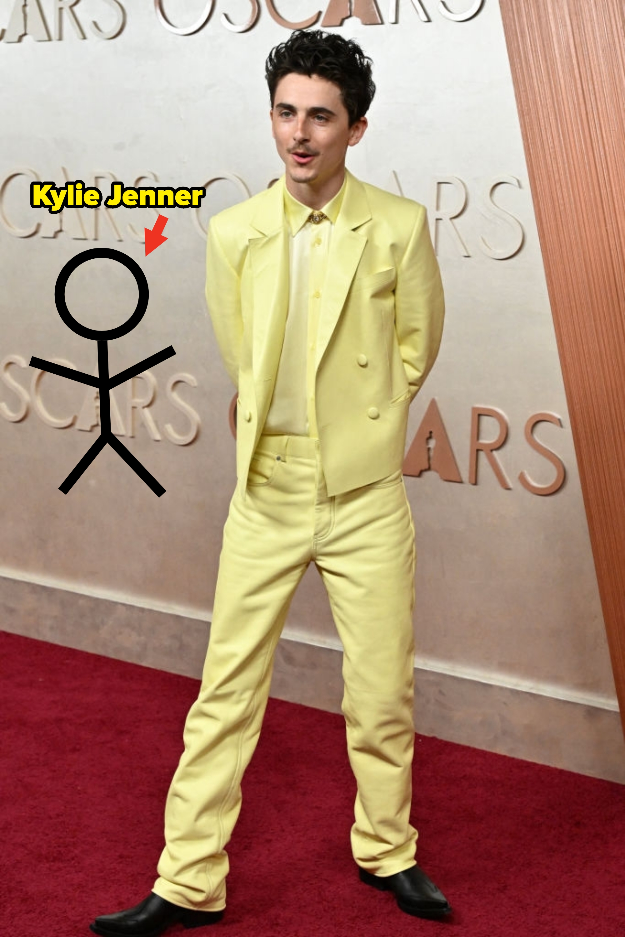 Person in a monochromatic suit on a red carpet, wearing a matching shirt and boots