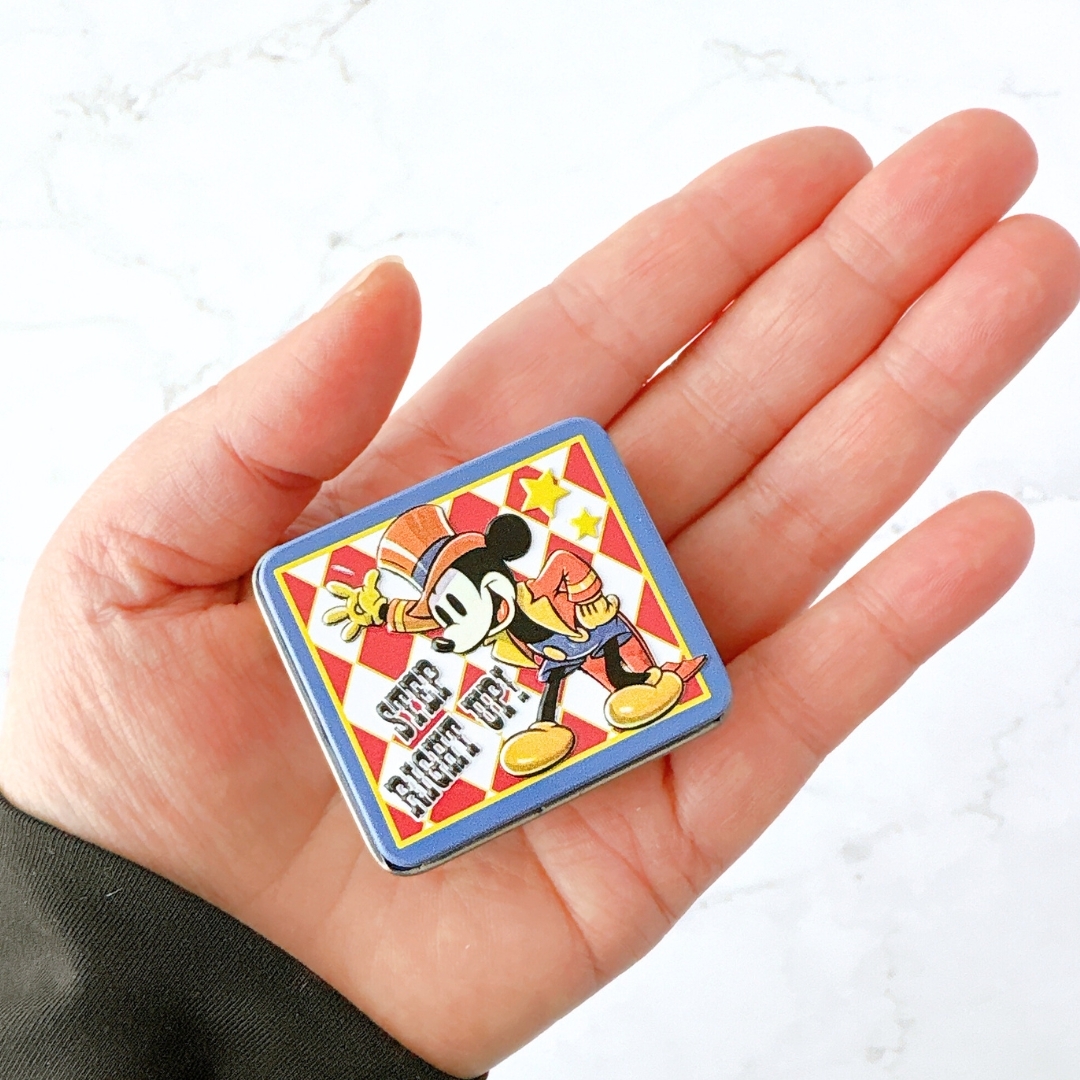 手のひらに乗ったディズニーキャラクターの缶ケース。レトロスタイルのミッキーマウスが描かれています。