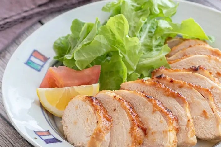 プレートにスライスされたグリルチキンとレタス、トマト、レモンが盛り付けられている。