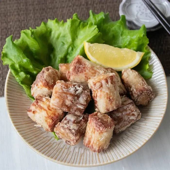 レタスとレモンのスライスを添えた揚げたタロイモキューブが盛られた皿。