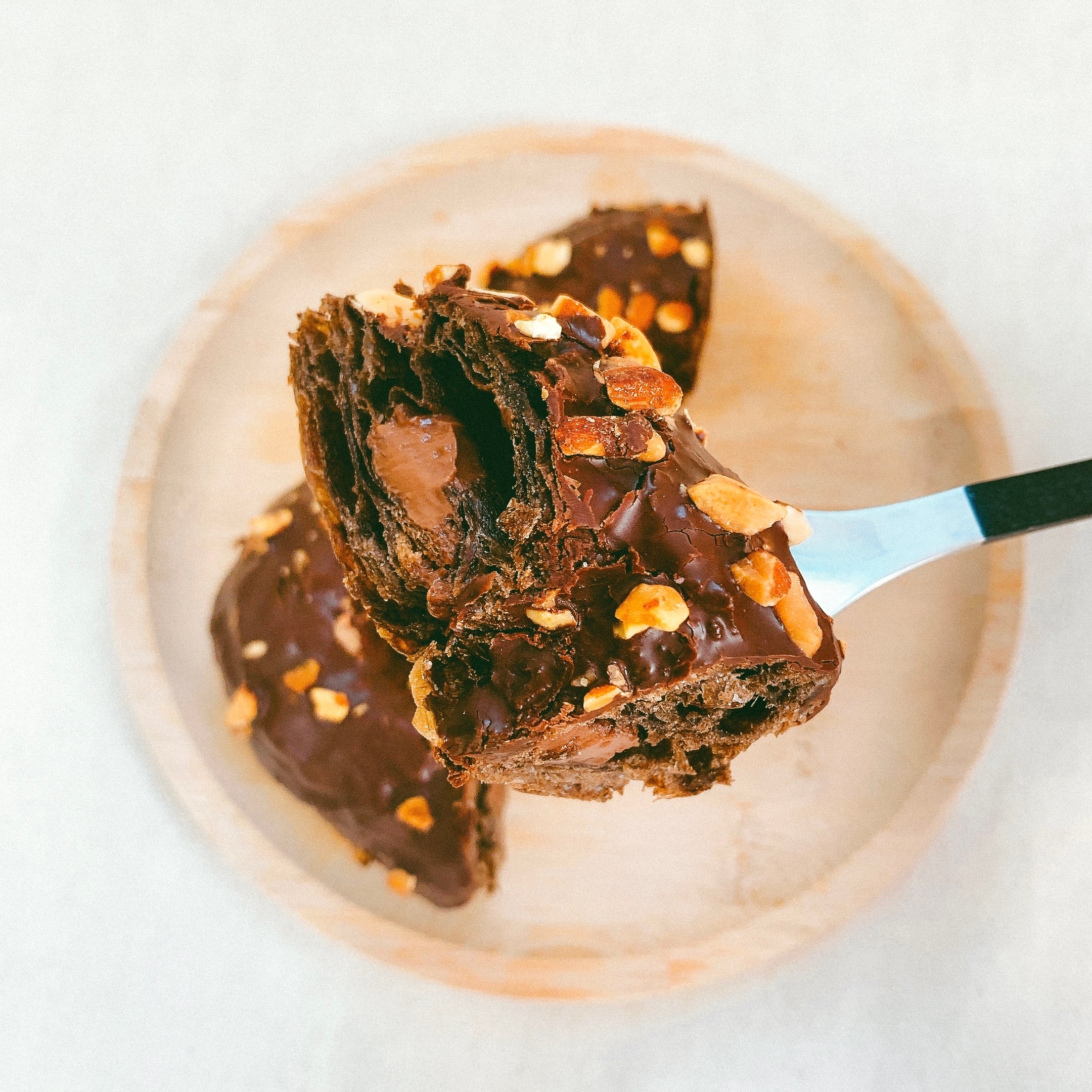 ナッツがトッピングされたチョコレートクロワッサンがフォークに乗った様子。