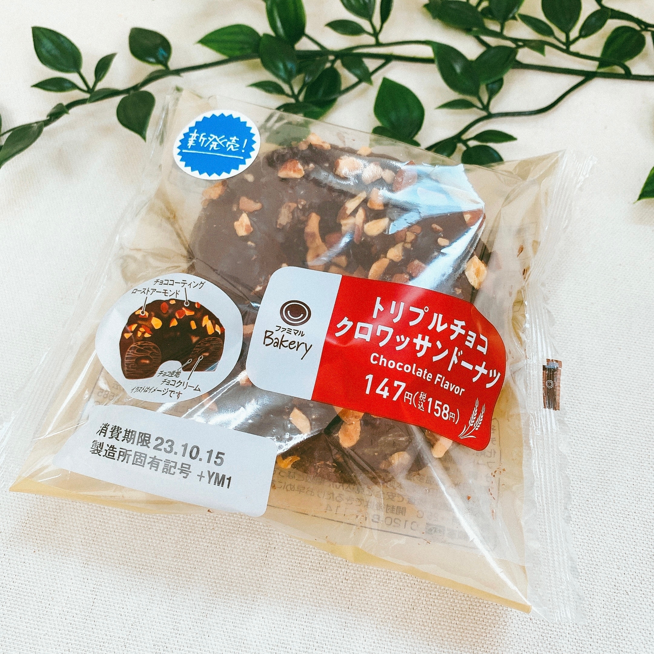 チョコクロワッサンドーナツの商品パッケージ。価格147円。葉っぱの飾りが背景にあります。