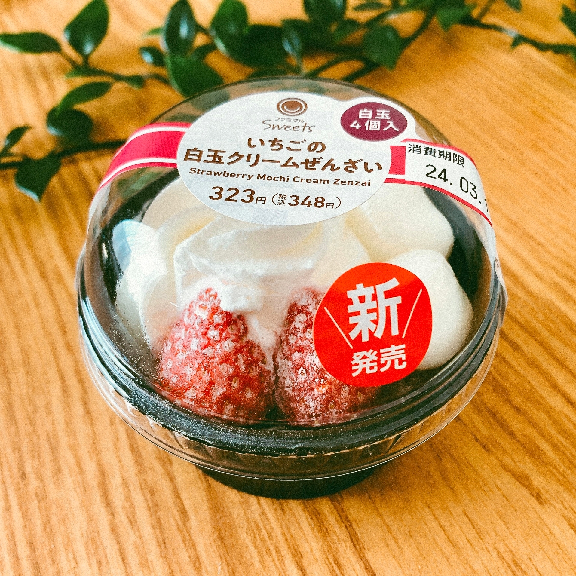 いちごの白玉クリームぜんざいのパッケージ。新発売と価格表示あり。背景に緑の飾り。
