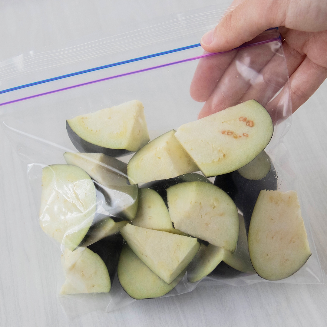 保存袋に入ったカットされたナス。手がバッグを持ち上げようとしている。