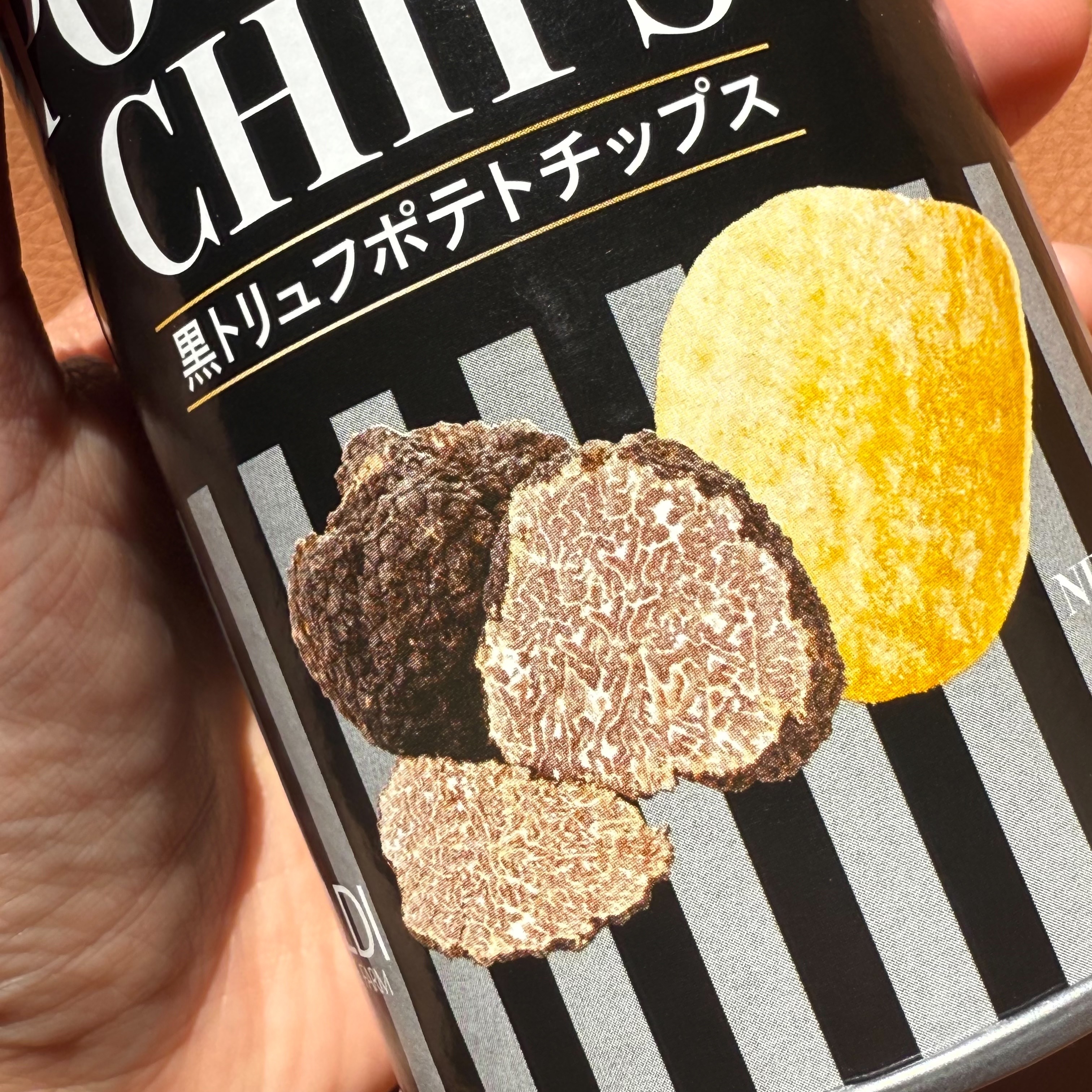 ポテトチップスのパッケージを手に持つ様子。黒トリュフとチップスの画像がデザインされています。