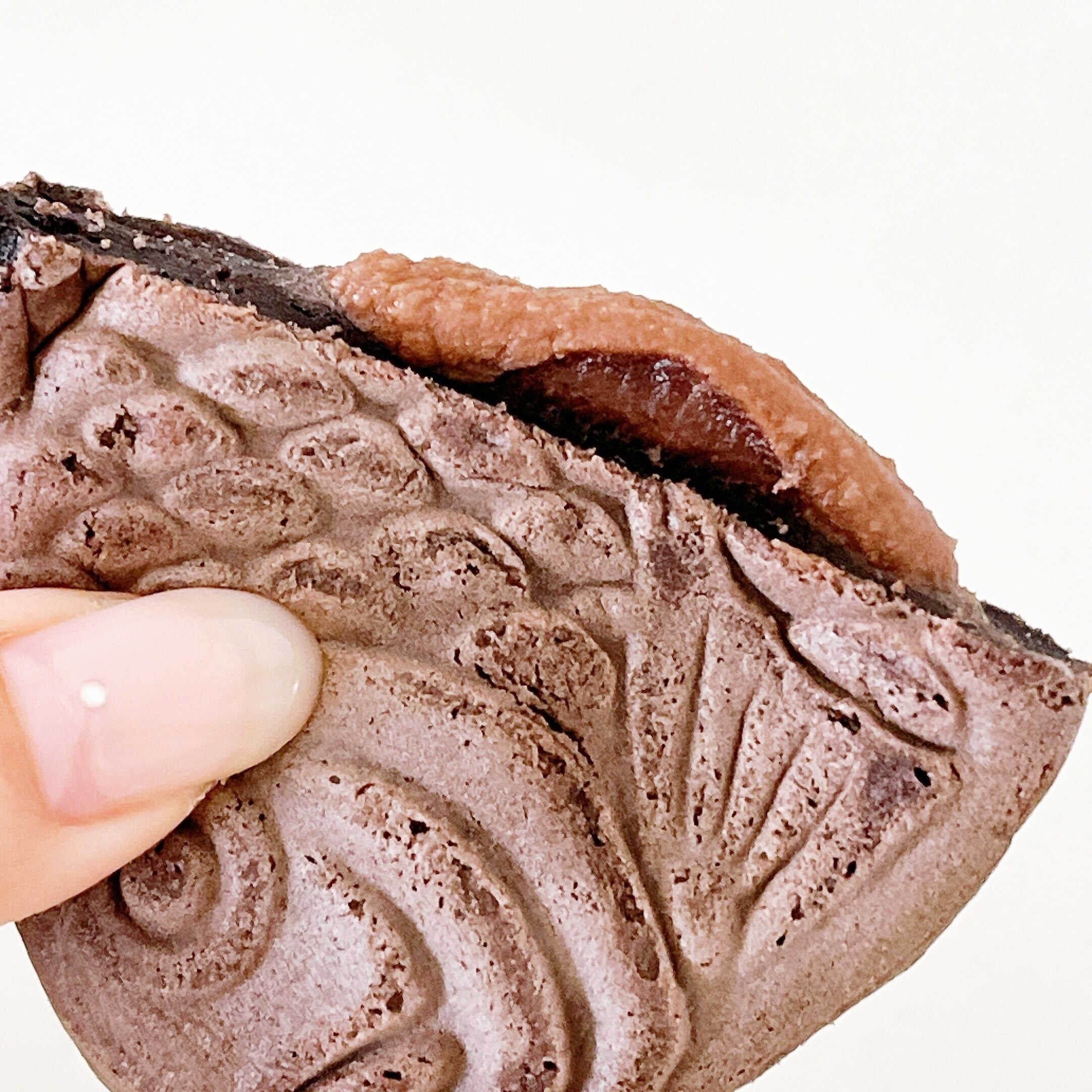 手に持たれた魚の形をした焼き菓子。中にあんこらしきものが見える。