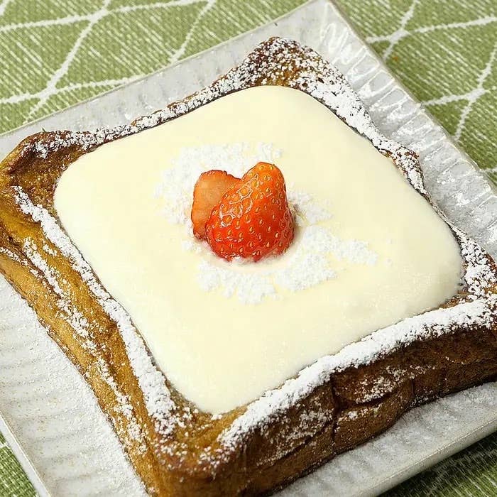 パンの上にクリームとイチゴがのったデザートが皿に盛られている。