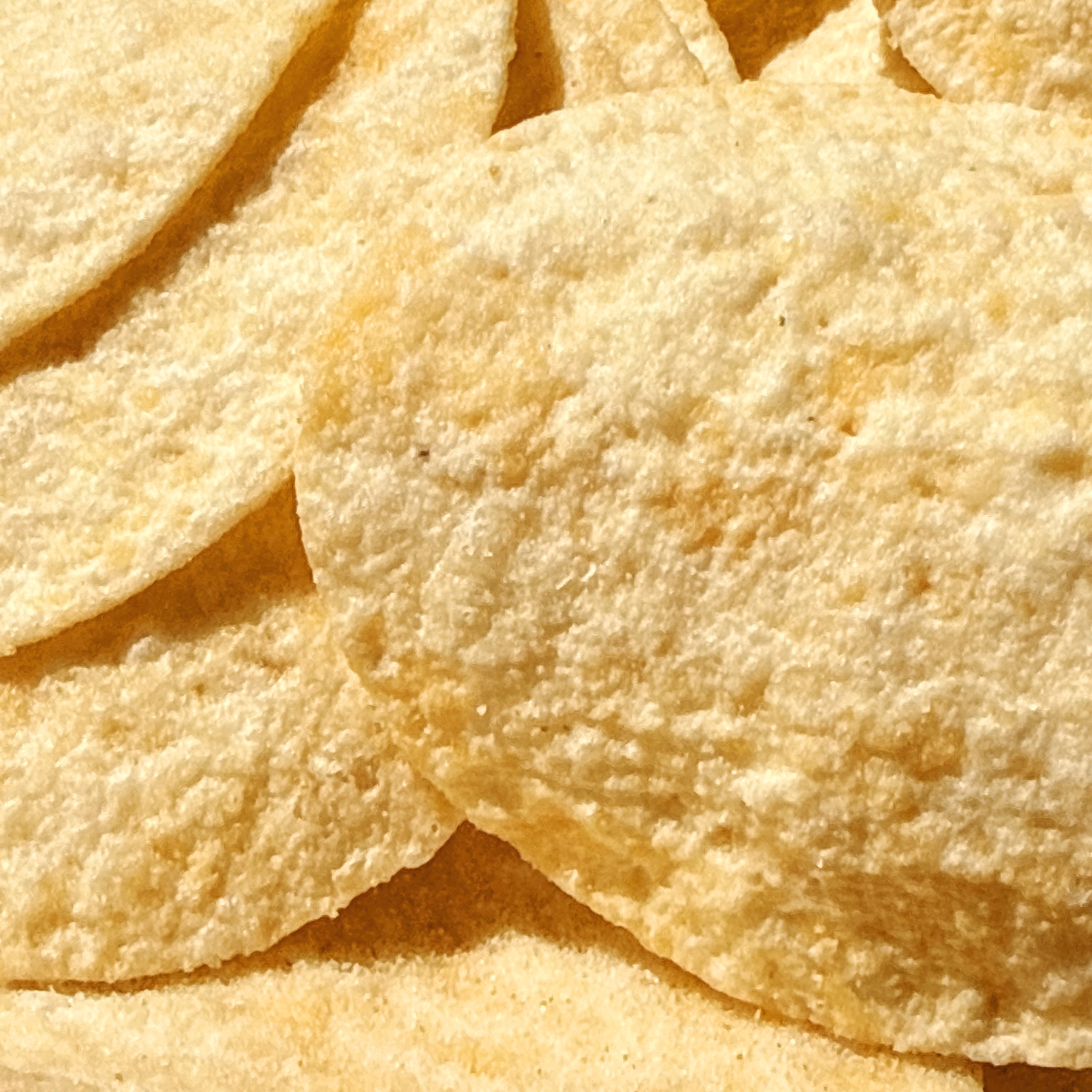 ポテトチップスの拡大写真。ザクザクとした食感が見て取れ、美味しさを強調する。