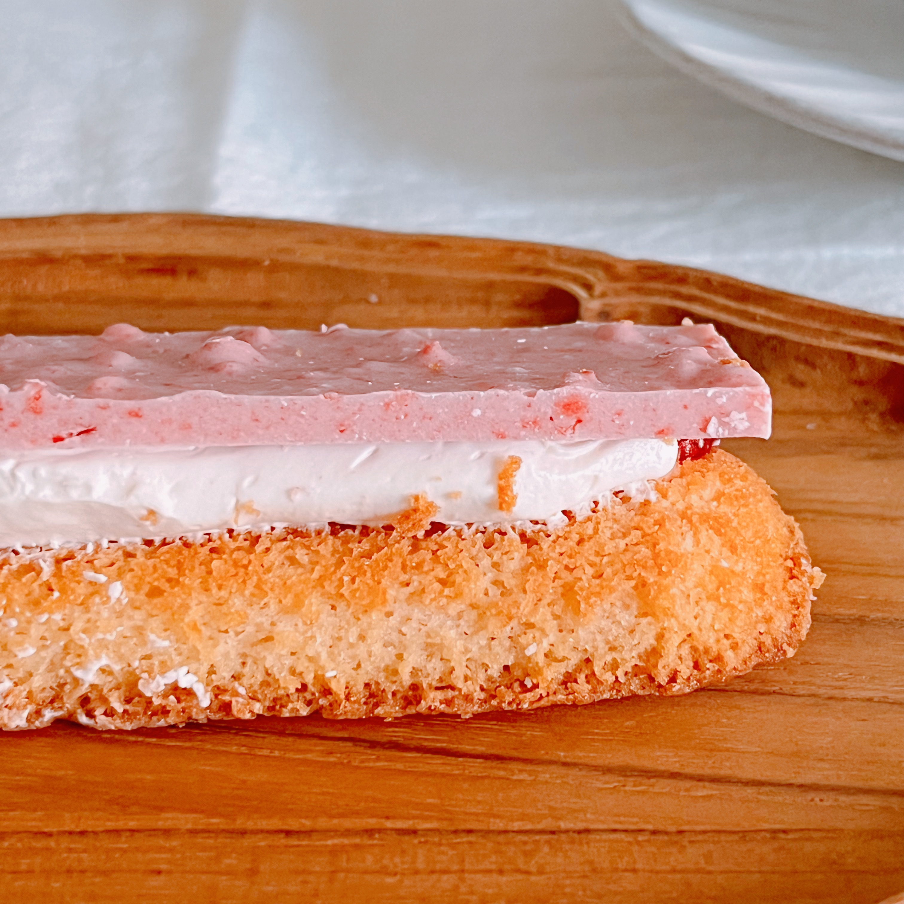 イチゴ風味のバーが乗ったケーキの一部が木製のボードに置かれている。