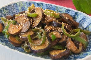 和風の皿に盛られたなすとピーマンの炒め物。ごまがかかっている。