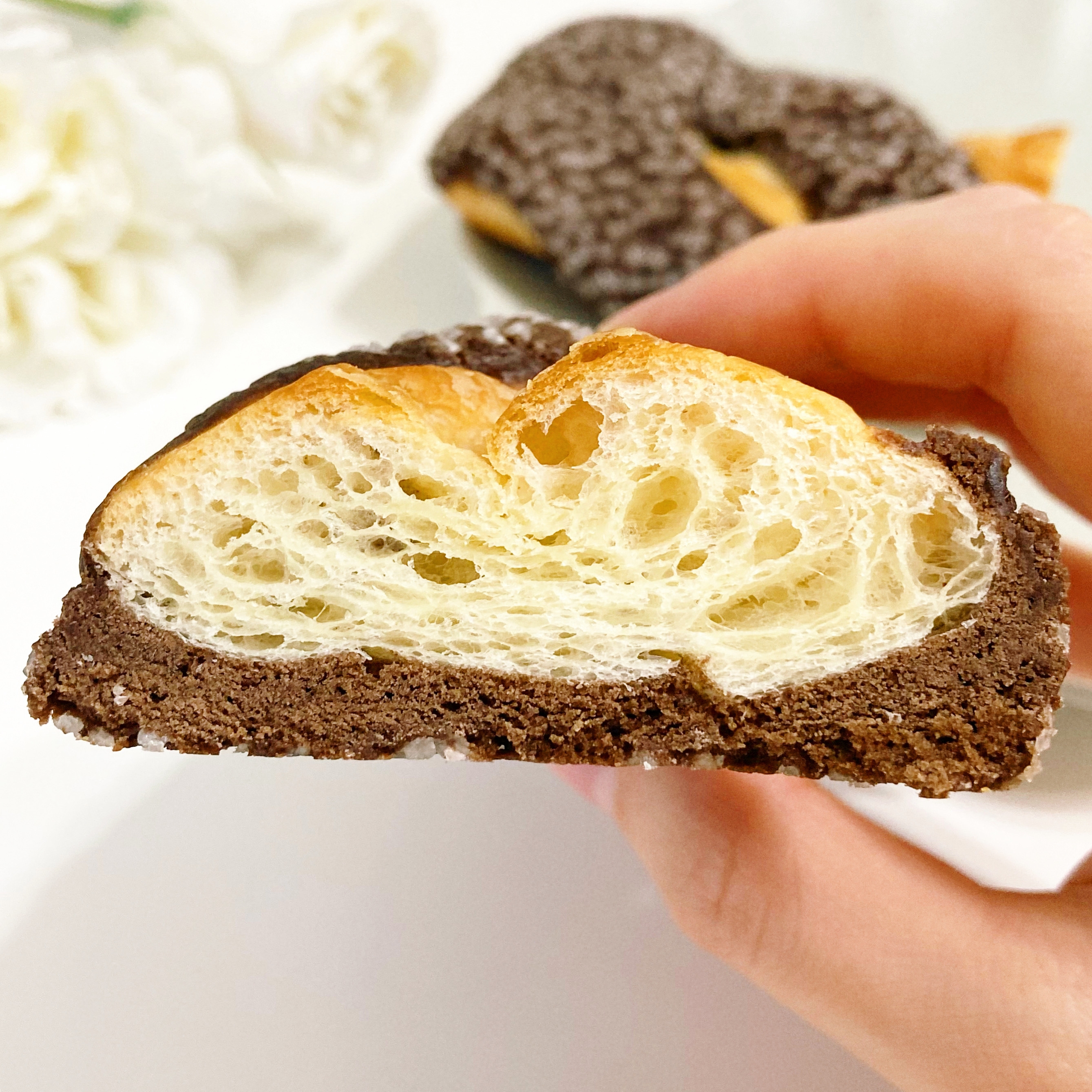 手に持ったチョコレートがけクロワッサンの断面が写っています。サクサクした層が見えます。