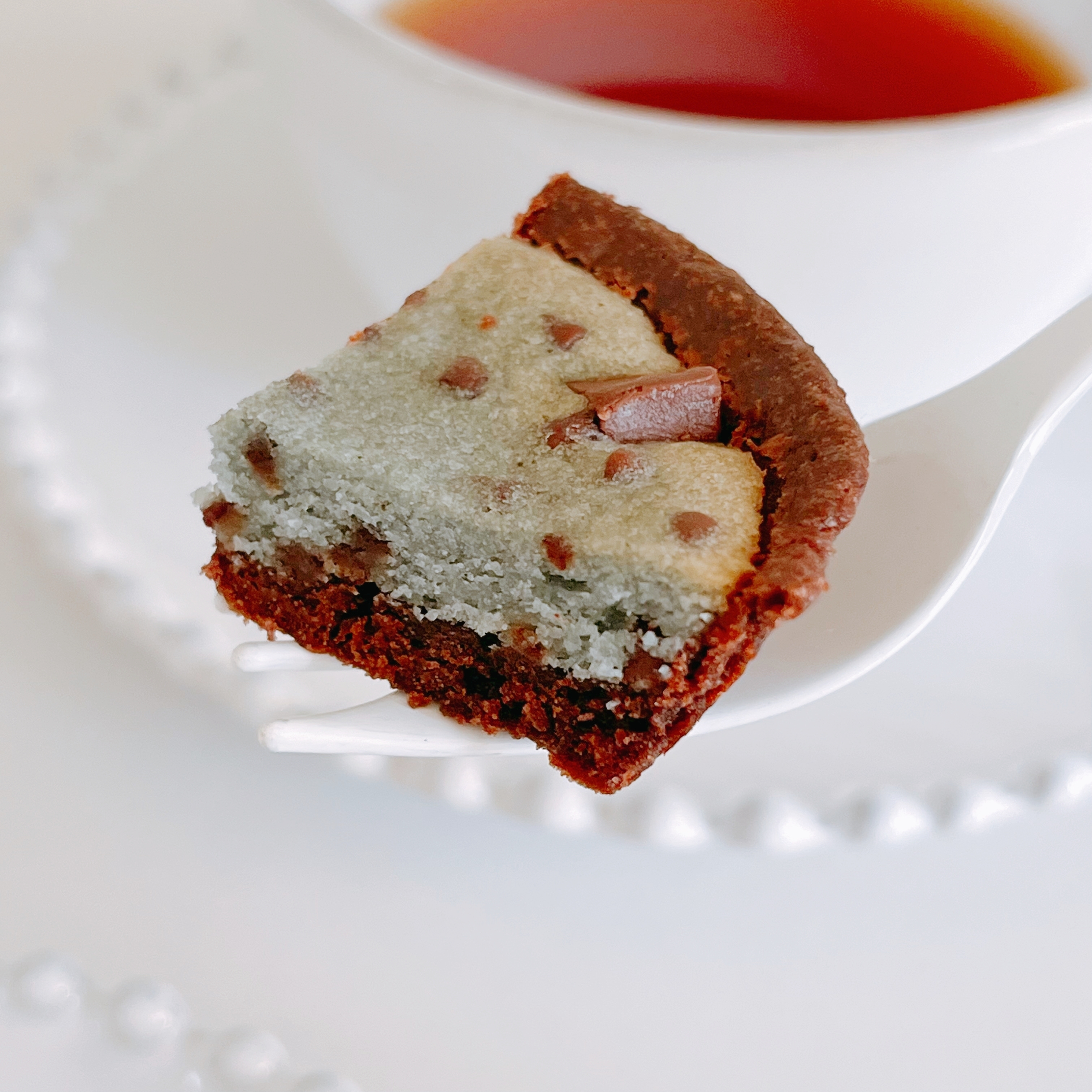 クッキー入りのチョコレートタルトが、紅茶のカップの横に置かれています。