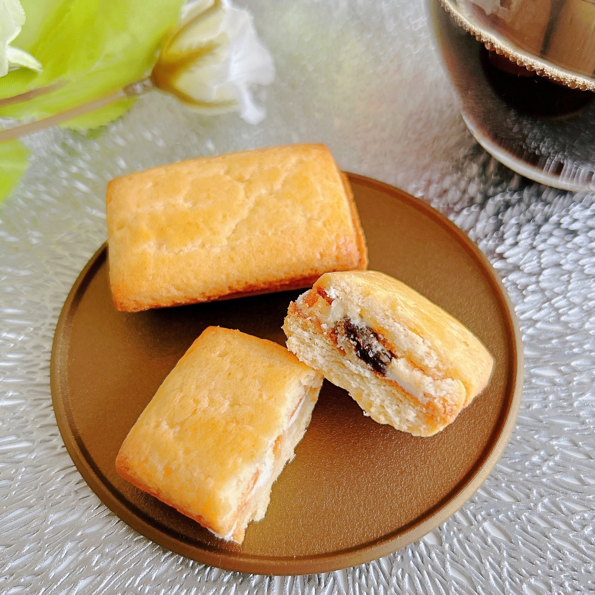 皿の上にある焼き菓子3つとコーヒーカップ。1つは半分に割られ、中のフィリングが見える。