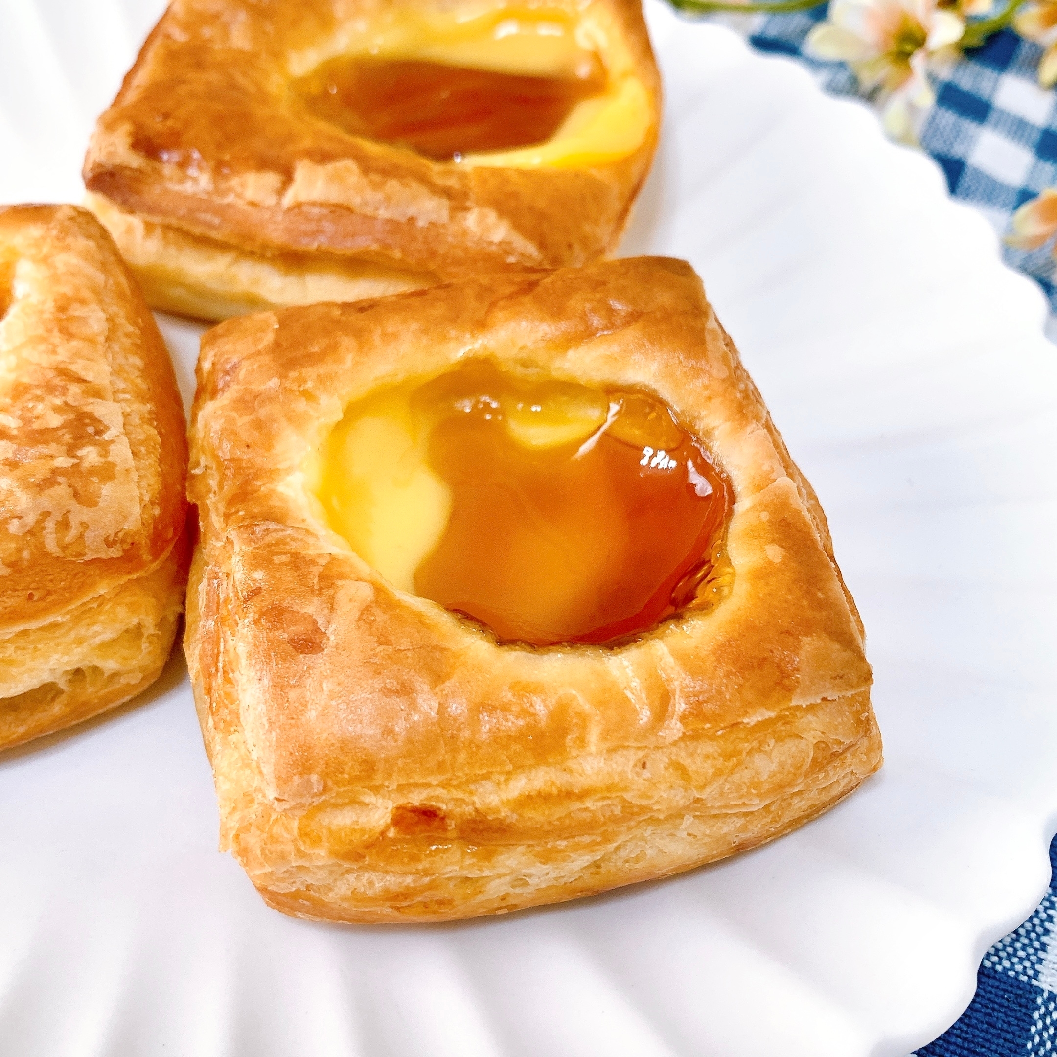 クリームとジャムがのったペストリーが白い皿に3つ並んでいます。