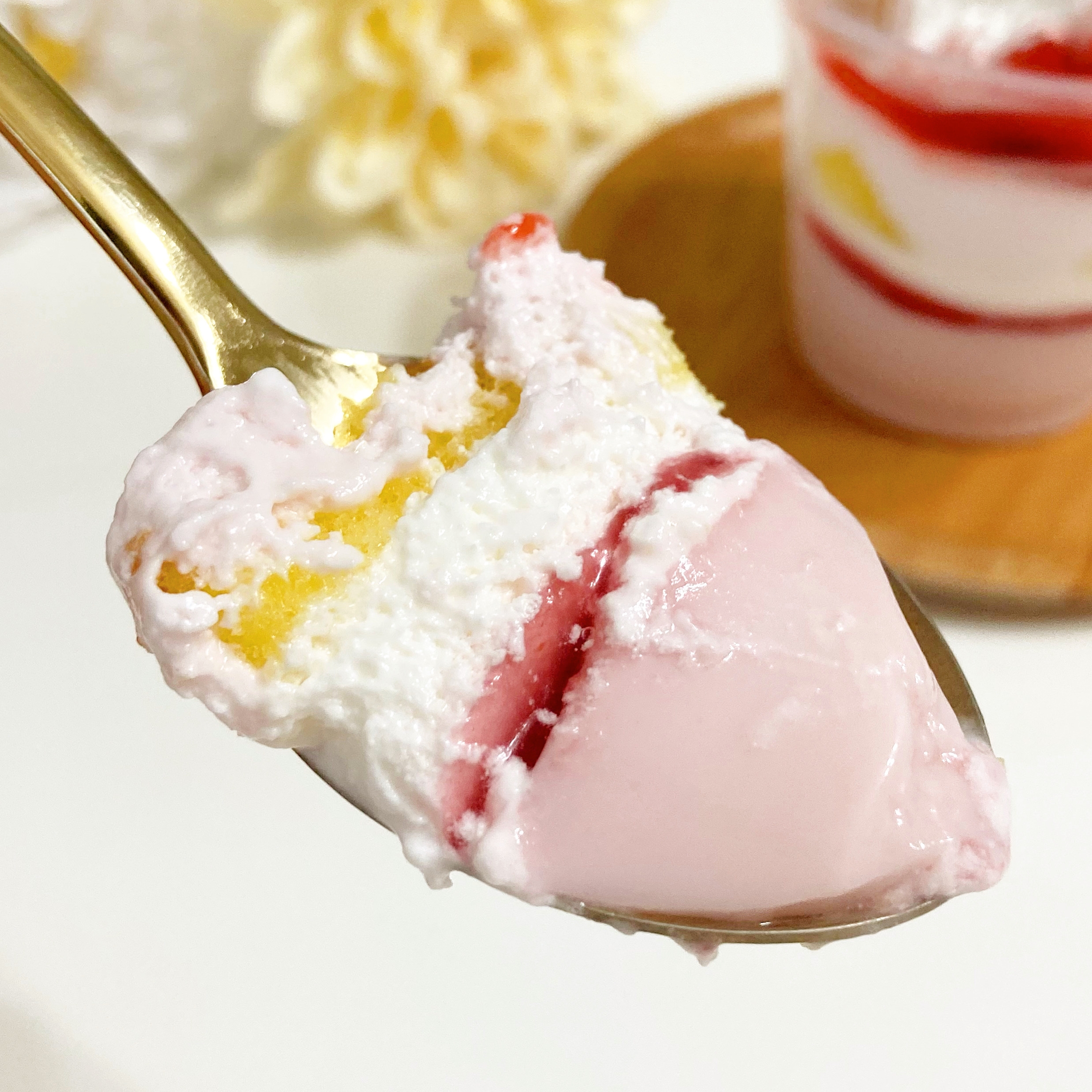 スプーンにのったピンク色のムースとクリーム、少しのスポンジケーキが見えます。デザートの層が美味しそうです。