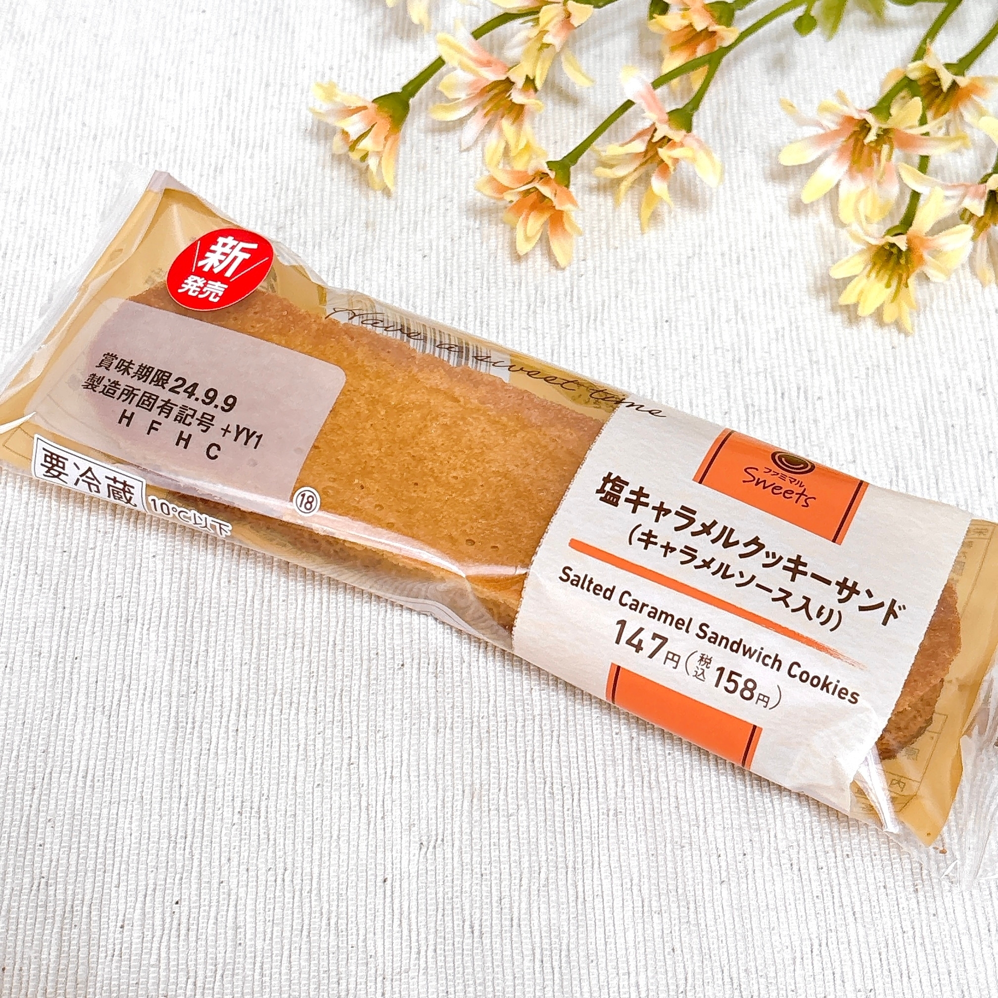 塩キャラメルクッキーサンドのパッケージ。包装には価格が表示されています。背景には花が飾られています。