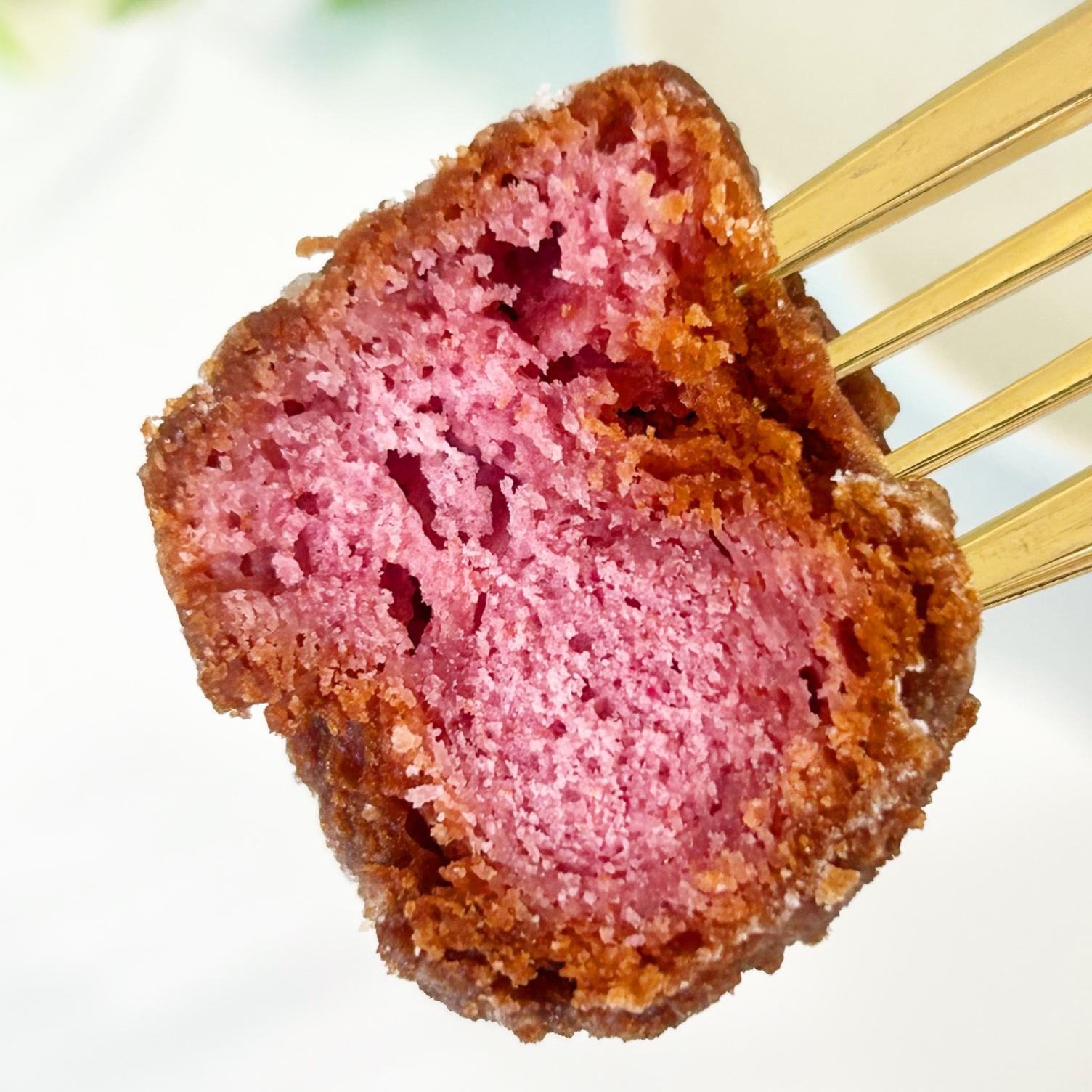 フォークで刺したピンク色の焼き菓子のクローズアップ写真。