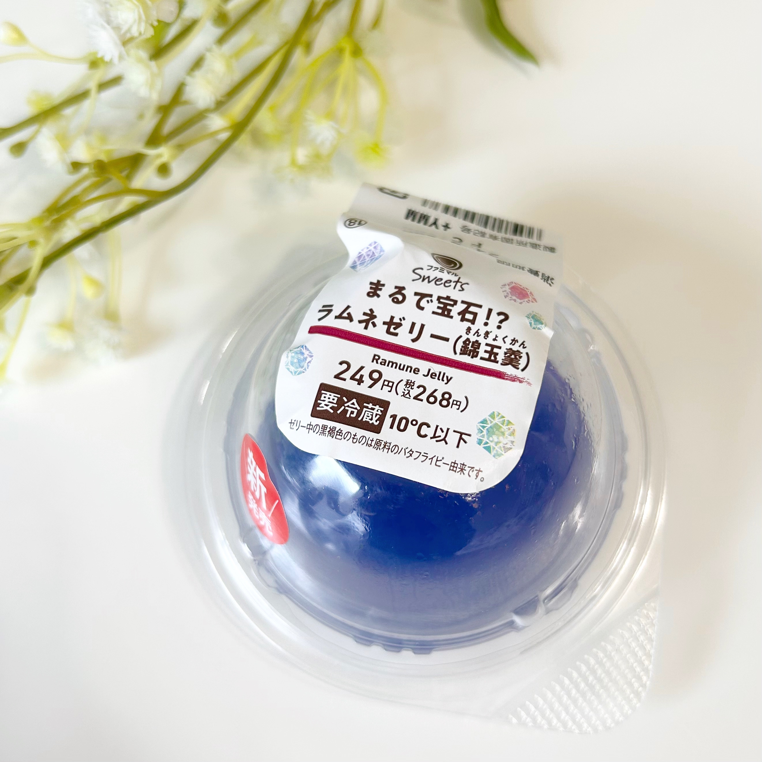 ラムネゼリーの商品パッケージ。テーブルに置かれ、白い花が隣に飾られています。