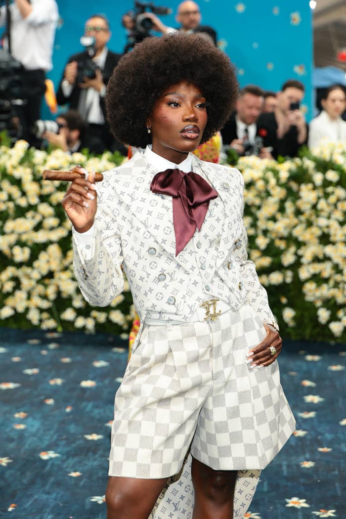 Doechii in Louis Vuitton outfit with a large bow and shorts, holding a cigar at the Met Gala